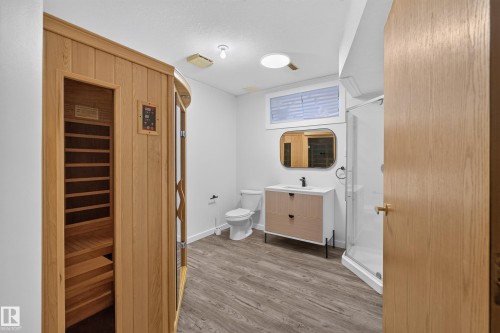 Wood-finish flooring, a contemporary vanity with a rectangular sink, a frameless glass shower enclosure, and a built-in sauna unit - 306 Twin Brooks Drive Nw, Edmonton, AB 