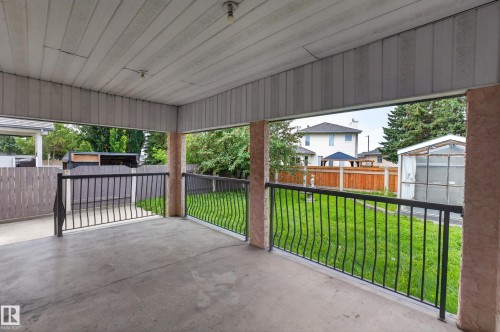 Covered concrete patio with black metal railings, textured columns, and a beadboard ceiling - 306 Twin Brooks Drive Nw, Edmonton, AB 