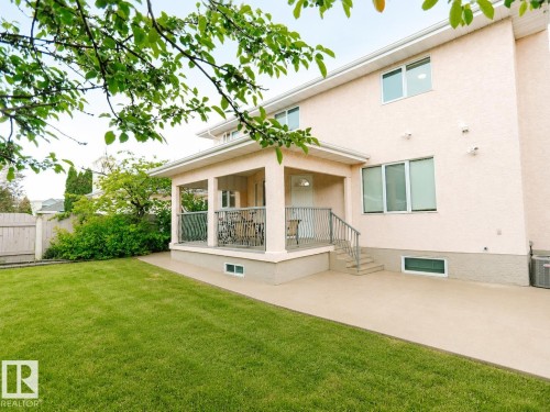 Expansive lawn area, stucco exterior, covered patio with metal railings, hardscaped patio, and multiple windows - 306 Twin Brooks Drive Nw, Edmonton, AB 