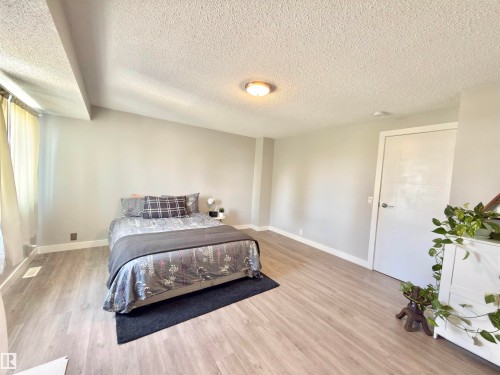 Light-toned wood-finish flooring, neutral wall paint, and a white paneled door - #13 18010 98 Av Nw Nw, Edmonton, AB - Indoor Photo Showing Bedroom