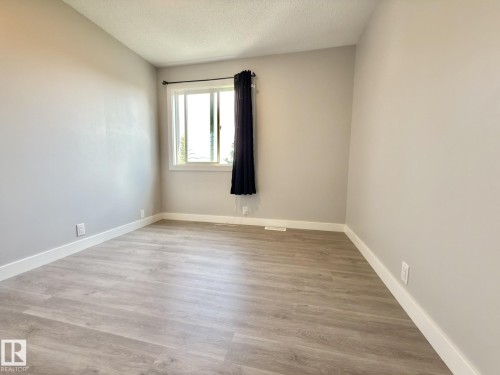 Light gray walls with white trim, wood-finish flooring, and a double-pane window - #13 18010 98 Av Nw Nw, Edmonton, AB - Indoor Photo Showing Other Room