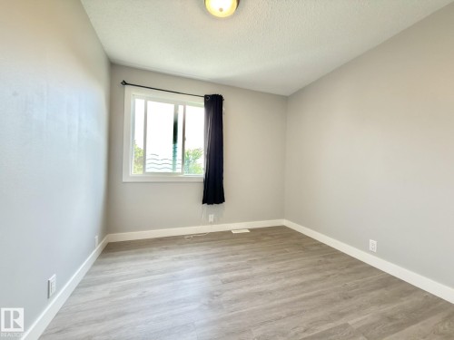 Wood-finish flooring, light gray wall paint, a single window with white trim, and a ceiling-mounted light fixture - #13 18010 98 Av Nw Nw, Edmonton, AB - Indoor Photo Showing Other Room