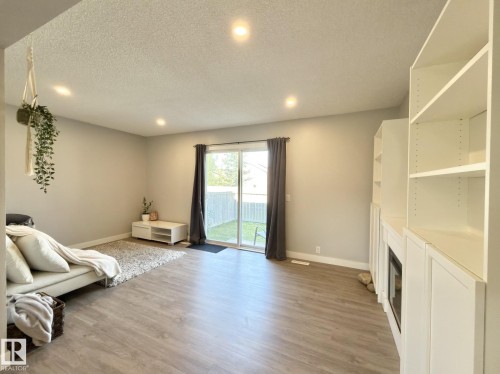 Recessed ceiling lighting, wood-finish flooring, sliding glass door, built-in shelving, and an integrated electric fireplace - #13 18010 98 Av Nw Nw, Edmonton, AB - Indoor