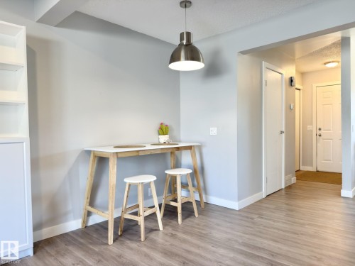 Wood-finish flooring throughout, modern pendant lighting, built-in shelving, and white interior doors - #13 18010 98 Av Nw Nw, Edmonton, AB - Indoor