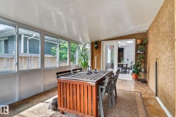Enclosed patio with full-height windows, textured wall finish, tiled flooring, and a vaulted ceiling - 