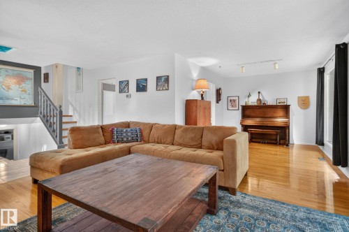 Light-toned wood-finish flooring, white walls, and a staircase with a wood railing - 12 Latimer Place, St. Albert, AB - Indoor Photo Showing Living Room