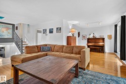 Light-toned wood-finish flooring, white walls, and a staircase with a wood railing - 