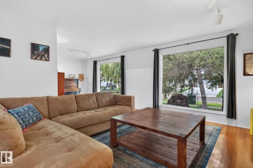 Hardwood-finish flooring, recessed lighting, and large windows with dark trim and drapes create a bright living area - 12 Latimer Place, St. Albert, AB - Indoor Photo Showing Living Room
