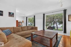 Hardwood-finish flooring, recessed lighting, and large windows with dark trim and drapes create a bright living area - 