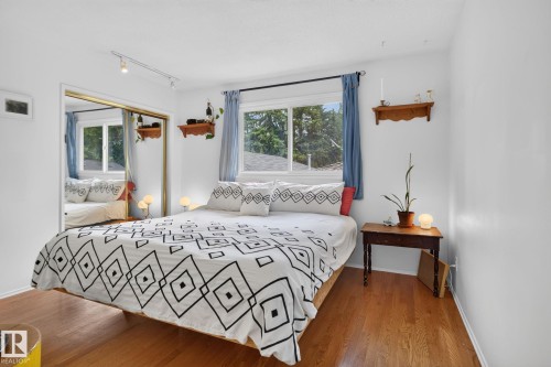 Bright interior with wood-finish flooring, a window offering natural light, and a mirrored sliding closet door - 12 Latimer Place, St. Albert, AB - Indoor Photo Showing Bedroom