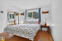 Bright interior with wood-finish flooring, a window offering natural light, and a mirrored sliding closet door - 