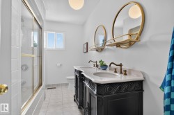 Dual vanity with ornate black cabinetry, white countertop, and brass-finish fixtures - 
