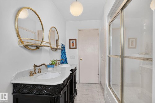 Dual vanity with a stone countertop, ornate dark wood cabinetry, and brass-tone fixtures - 12 Latimer Place, St. Albert, AB - Indoor