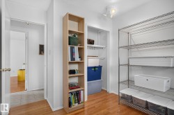 Hardwood flooring throughout, with a recessed closet featuring shelving, and a built-in wood-finish shelving unit - 