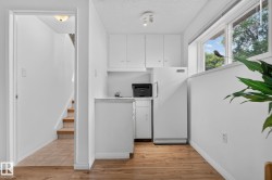 Compact kitchenette featuring white cabinetry, a sink, and a refrigerator - 