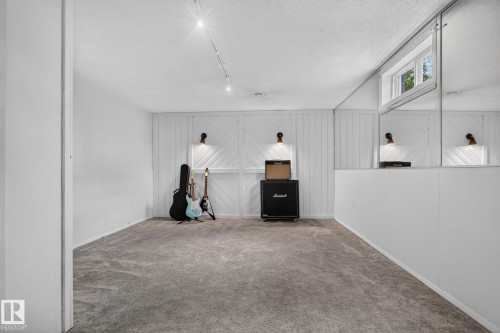 Recessed window with exterior light, mirrored wall panels, accent wall with sconce lighting, track lighting, and wall-to-wall carpeting - 12 Latimer Place, St. Albert, AB - Indoor Photo Showing Other Room