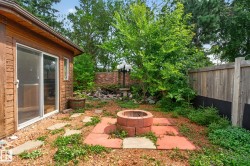 Sliding glass door entry, brick fire pit, stone paver patio, wood privacy fencing, and lush landscaping - 