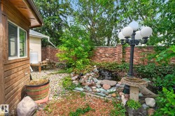 Exterior landscaping featuring a water feature, stone accents, and a brick privacy wall - 