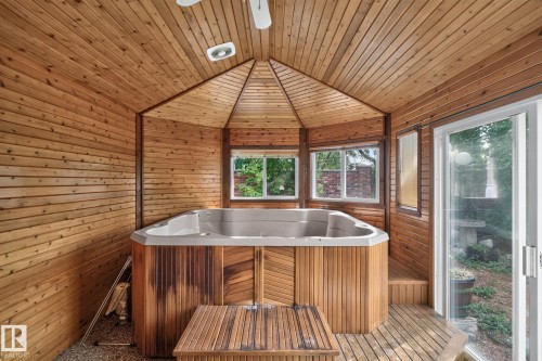 Enclosed wood-paneled space featuring a built-in spa, slatted wood flooring, multiple windows, and a sliding glass door - 12 Latimer Place, St. Albert, AB - 