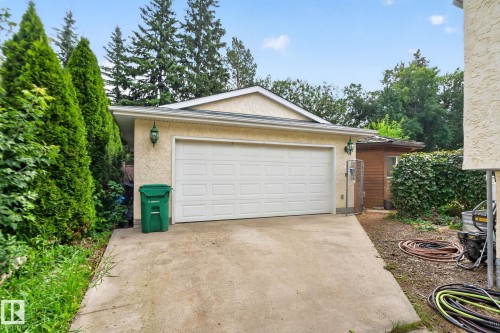 Attached garage with a white sectional door, concrete driveway, and exterior wall lanterns - 12 Latimer Place, St. Albert, AB - Outdoor