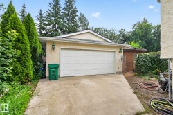 Attached garage with a white sectional door, concrete driveway, and exterior wall lanterns - 