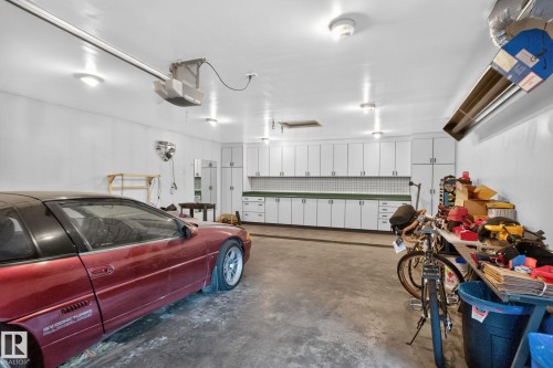 Garage featuring extensive built-in cabinetry, overhead lighting, garage door opener mechanism, and concrete flooring - 12 Latimer Place, St. Albert, AB - Indoor Photo Showing Garage