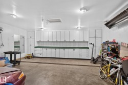Integrated garage storage with white cabinetry and green countertops - 