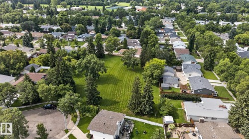 Expansive green space with mature trees, surrounded by residential properties, featuring a paved street and abundant foliage - 12 Latimer Place, St. Albert, AB - Outdoor With View