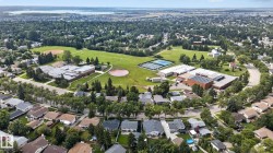 Aerial perspective showcasing an expansive green space with sports fields, tennis courts, and mature trees - 