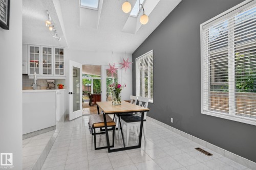 Vaulted ceiling with skylights, track lighting, two windows with blinds, tiled flooring, and a glass-paneled door - 12 Latimer Place, St. Albert, AB - Indoor