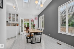 Vaulted ceiling with skylights, track lighting, two windows with blinds, tiled flooring, and a glass-paneled door - 