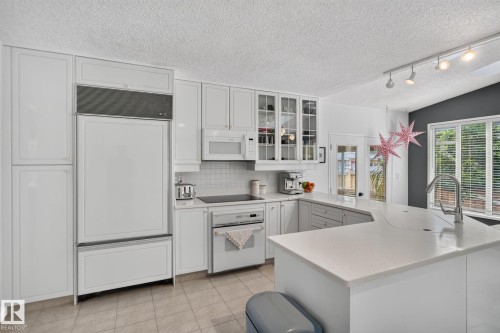 White cabinetry, integrated panel-ready refrigerator, built-in cooktop, and an island with a breakfast bar - 12 Latimer Place, St. Albert, AB - Indoor Photo Showing Kitchen