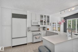 White cabinetry, integrated panel-ready refrigerator, built-in cooktop, and an island with a breakfast bar - 