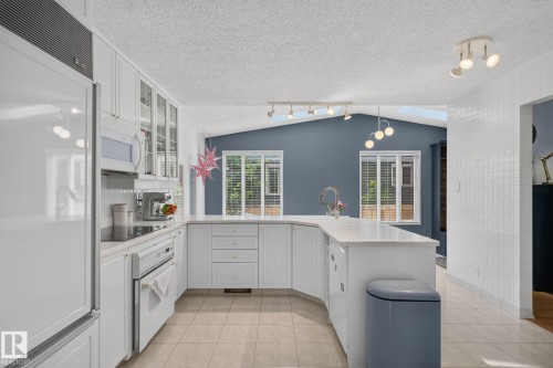 Kitchen featuring white cabinetry, integrated appliances, an island with an undermount sink, and tile flooring - 12 Latimer Place, St. Albert, AB - Indoor Photo Showing Kitchen
