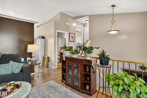 Vaulted ceiling, wood-finish flooring, interior railing with wood top and metal spindles, recessed lighting, and a pendant light fixture - #9 6506 47 St, Cold Lake, AB - Indoor Photo Showing Other Room