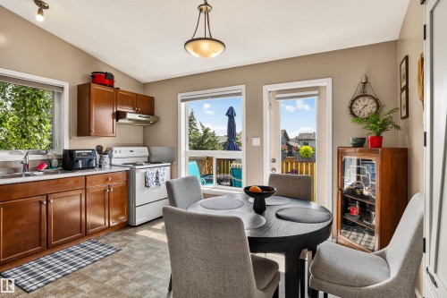 Vaulted ceiling kitchen featuring wood cabinetry, laminate countertops, a white electric range, and a glass-paneled exterior door - #9 6506 47 St, Cold Lake, AB - Indoor Photo Showing Kitchen With Double Sink