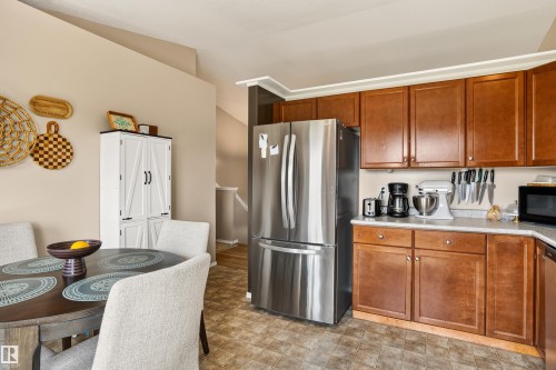 Kitchen featuring wood-finish cabinetry, stainless steel refrigerator, and light-toned countertops - #9 6506 47 St, Cold Lake, AB - Indoor Photo Showing Kitchen