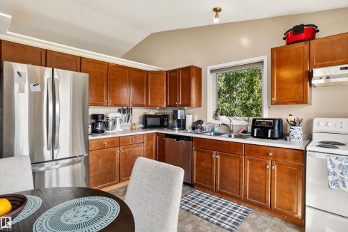 Kitchen featuring wood cabinetry, stainless steel refrigerator, white countertops, and a single basin sink - #9 6506 47 St, Cold Lake, AB - Indoor Photo Showing Kitchen With Double Sink