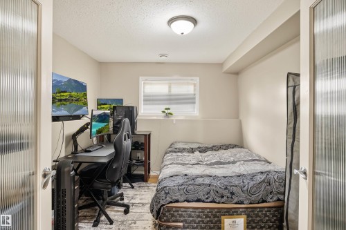 Recessed window with blinds, ceiling-mounted light fixture, and textured glass panel doors - #9 6506 47 St, Cold Lake, AB - Indoor Photo Showing Bedroom