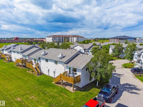 Multiple residential units featuring private decks with wooden railings and stairs, individual exterior entrances, and pitched roofs with visible chimneys - #9 6506 47 St, Cold Lake, AB - Outdoor With View