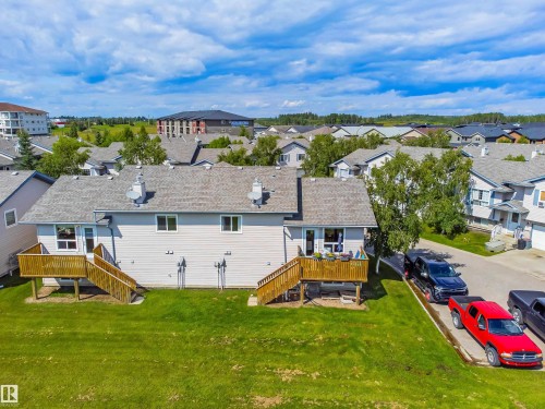 Two private decks with wood railings, expansive green space, light-toned exterior siding, and a shingled roof - #9 6506 47 St, Cold Lake, AB - Outdoor With View
