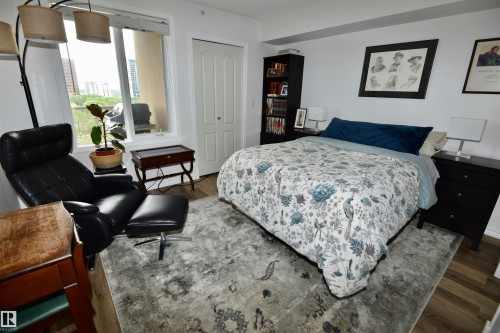 Wide plank wood-finish flooring, white painted walls, and a large window with a white frame - #706 9741 110 St Nw, Edmonton, AB - Indoor Photo Showing Bedroom