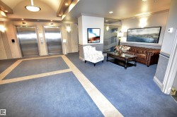 Lobby area featuring two stainless steel elevators, patterned blue carpeting with a light-colored inlay, and recessed lighting - 
