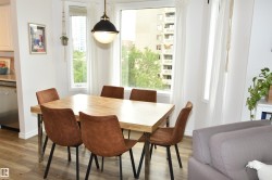 Dining area with wood-finish flooring, a contemporary pendant light fixture, and large windows - 