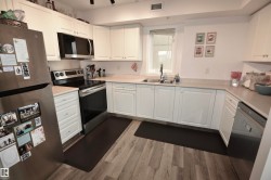 Kitchen featuring white cabinetry, light countertops, wood-finish flooring, stainless steel appliances, and a window above the sink - 