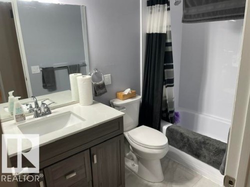 Modern vanity with a white countertop and integrated sink, chrome faucet, wall-mounted mirror, and a white bathtub with an integrated shower head - 27 Gatewood Avenue, St. Albert, AB - Indoor Photo Showing Bathroom
