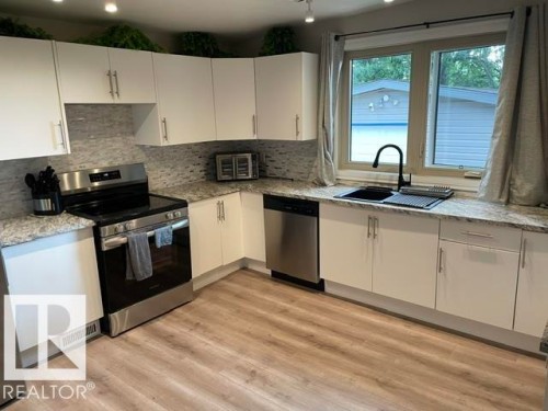 White shaker cabinetry, gray patterned countertops, stainless steel appliances, modern black sink and faucet, wood-finish flooring - 27 Gatewood Avenue, St. Albert, AB - Indoor Photo Showing Kitchen With Double Sink