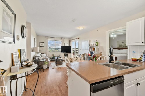 Kitchen island with integrated stainless steel sink and modern black faucet - #407 4309 33 St, Stony Plain, AB - Indoor Photo Showing Kitchen With Double Sink