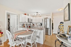 Kitchen featuring white cabinetry, stainless steel appliances, a center island with seating, and wood-finish flooring - 