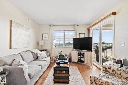 Light wood-finish flooring, white painted walls, window with blinds, and white-framed sliding glass door - #407 4309 33 St, Stony Plain, AB - Indoor Photo Showing Living Room